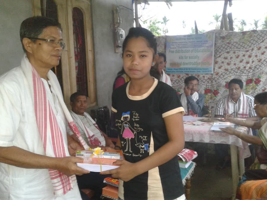 A student receiving educational materials from a member of SRI SRI SANTA SAMAJ